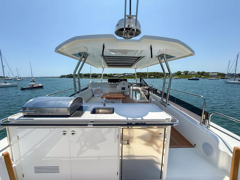 Slide: The Image of 2026 Beneteau Swift Trawler 54 yacht deck with outdoor kitchen and seating, overlooking serene waters. - 26
