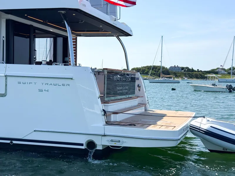 Slide: The Image of 2026 Beneteau Swift Trawler 54 docked, showcasing rear deck and open water view. - 31
