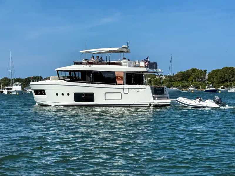 Slide: The Image of 2026 Beneteau Swift Trawler 54 cruising on a sunny day with a small boat in tow. - 33