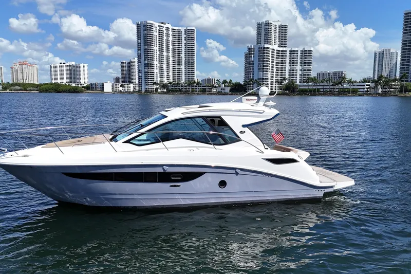 Slide: The Image of 2017 Sea Ray Sundancer 350 Coupe yacht on water with city skyline backdrop. - 105