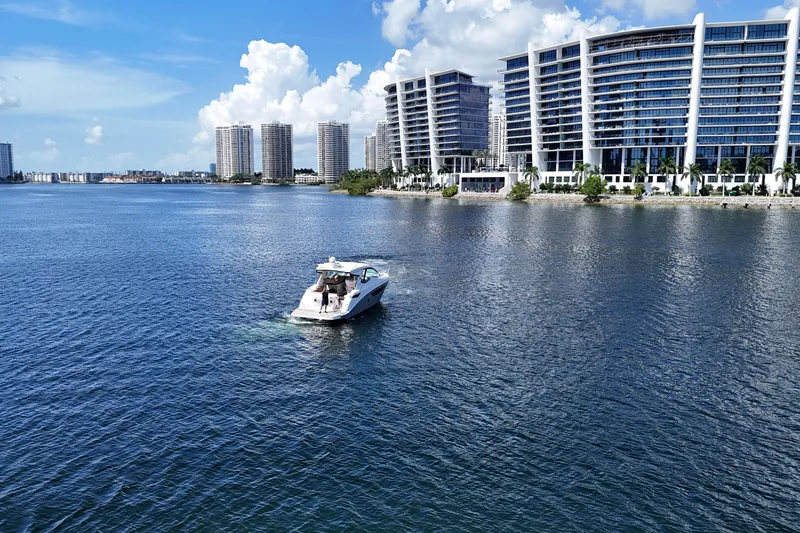 Slide: The Image of 2017 Sea Ray Sundancer 350 Coupe cruising near modern waterfront buildings. - 108
