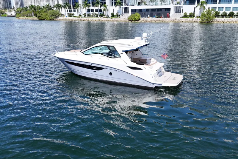 Slide: The Image of 2017 Sea Ray Sundancer 350 Coupe cruising on a scenic waterfront with modern buildings. - 12