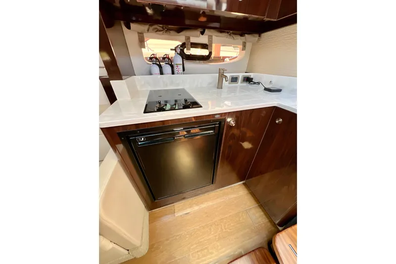 Slide: The Image of 2017 Sea Ray Sundancer 350 Coupe kitchen with stove, fridge, and sleek cabinetry. - 121