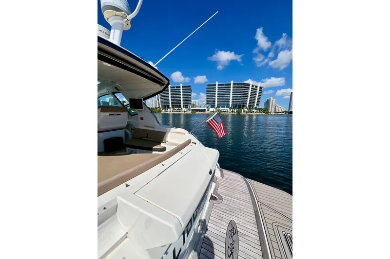Slide: The Image of 2017 Sea Ray Sundancer 350 Coupe docked with city skyline and American flag. - 18