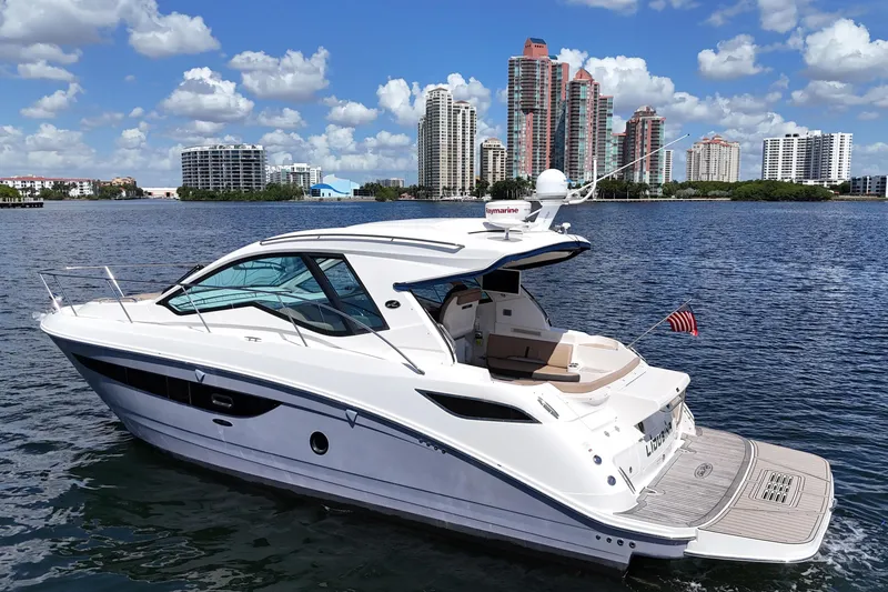 Slide: The Image of 2017 Sea Ray Sundancer 350 Coupe yacht on water with city skyline backdrop. - 4