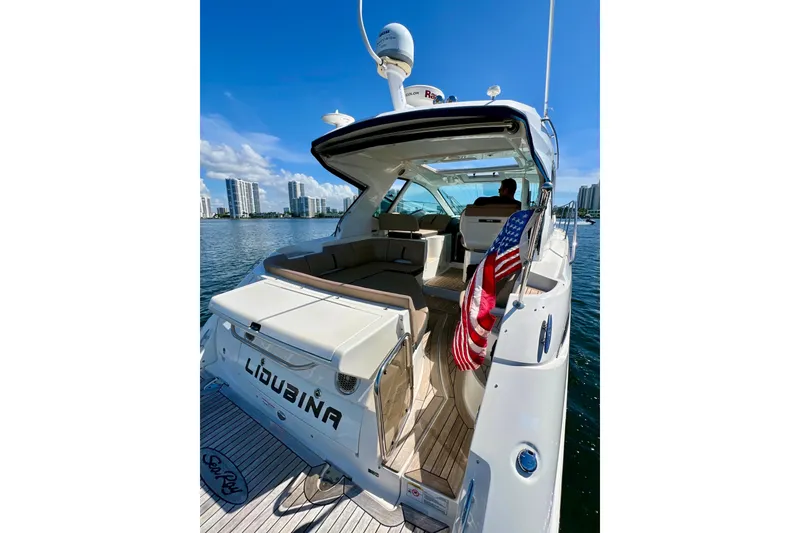 Slide: The Image of 2017 Sea Ray Sundancer 350 Coupe yacht with American flag, docked near city skyline. - 65