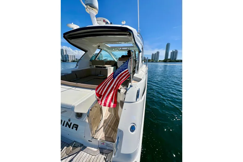 Slide: The Image of 2017 Sea Ray Sundancer 350 Coupe yacht with American flag, city skyline in background. - 66