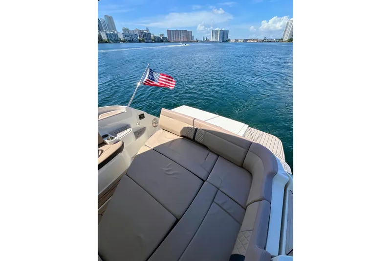 Slide: The Image of 2017 Sea Ray Sundancer 350 Coupe on water, American flag, city skyline in background. - 68