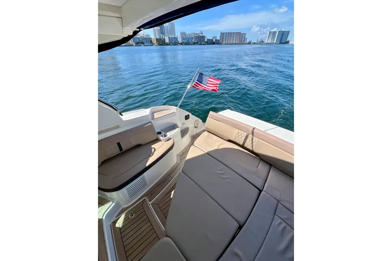 Slide: The Image of 2017 Sea Ray Sundancer 350 Coupe on water, American flag, city skyline in background. - 73