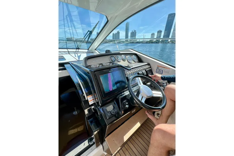 Slide: The Image of Cockpit view of 2017 Sea Ray Sundancer 350 Coupe with city skyline in background. - 79