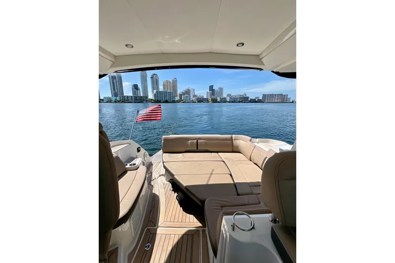 Slide: The Image of 2017 Sea Ray Sundancer 350 Coupe with city skyline view, featuring luxurious seating and American flag. - 88