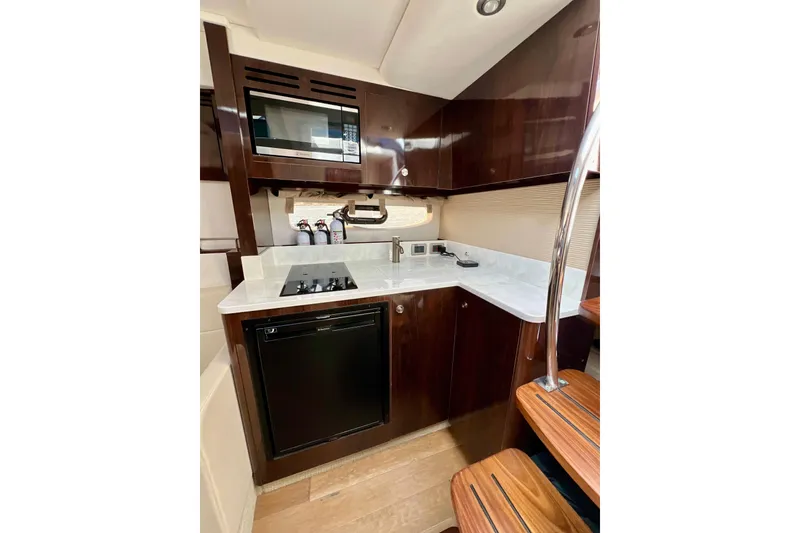 Slide: The Image of 2017 Sea Ray Sundancer 350 Coupe kitchen with dark wood cabinets and modern appliances. - 96