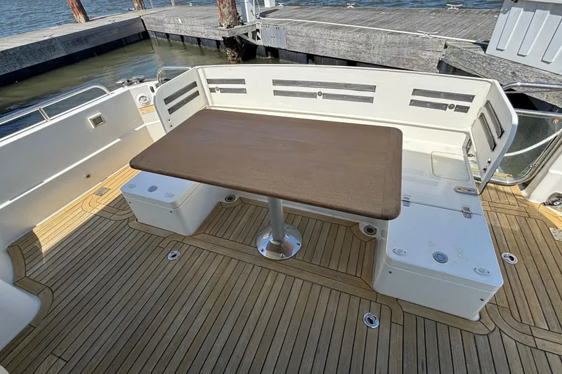 Slide: The Image of 2019 Sabre 45 Salon Express yacht deck with wooden table and seating area. - 7