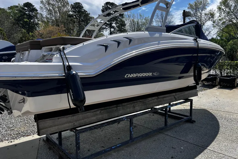Slide: The Image of 2022 Chaparral 23 SSi boat on display stand, outdoors with trees in background. - 4