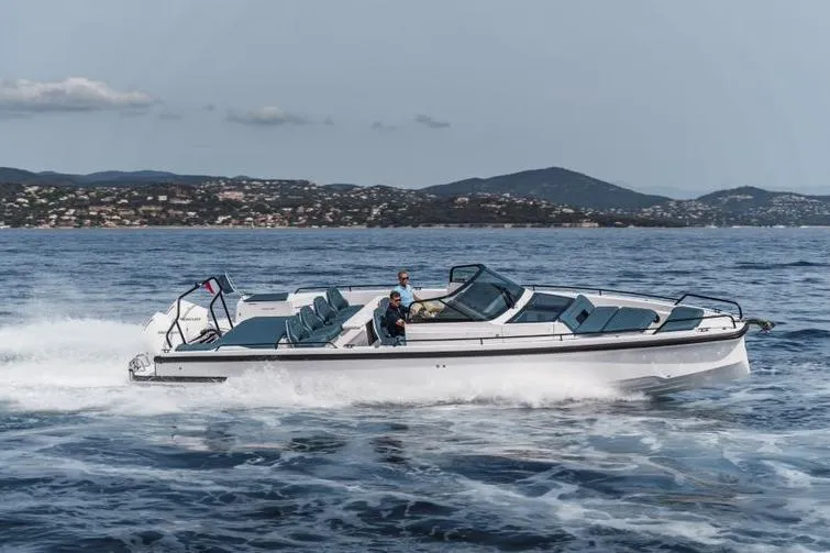 The Image of 2027 Axopar 37 Spyder cruising on open water with scenic coastal backdrop. - 0