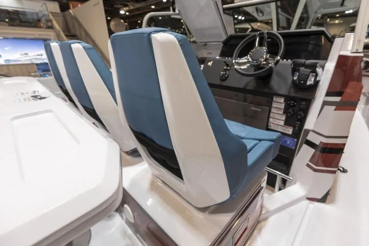 Slide: The Image of 2027 Axopar 37 Spyder boat interior with blue and white seats and steering console. - 6