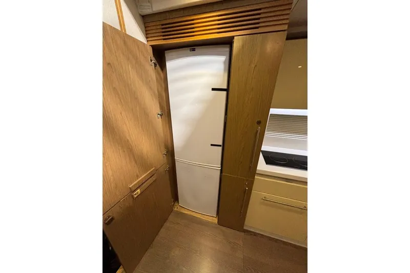 Slide: The Image of 2014 Beneteau Gran Turismo 49 yacht interior with wooden cabinetry and built-in refrigerator. - 55