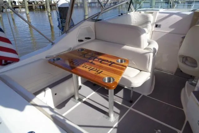 Slide: The Image of 2002 Chaparral Signature 260 boat interior with seating and wooden table, docked by the water. - 11