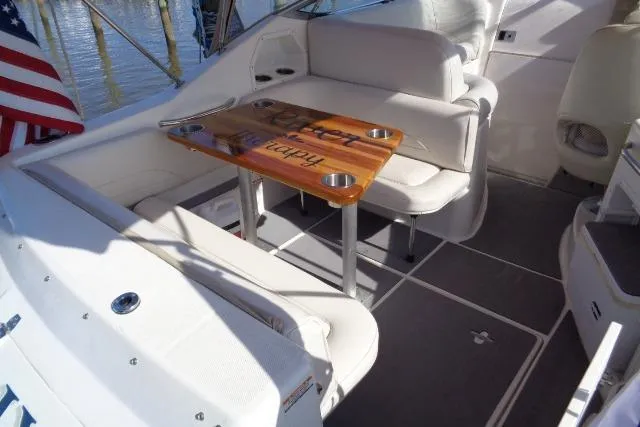 Slide: The Image of 2002 Chaparral Signature 260 boat interior with seating and wooden table, docked by water. - 14