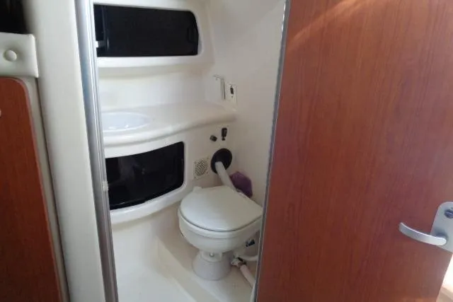 Slide: The Image of 2002 Chaparral Signature 260 boat bathroom with toilet and sink, featuring wooden door. - 18