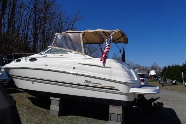 Slide: The Image of 2002 Chaparral Signature 260 boat on blocks, with canopy and American flag, under clear blue sky. - 3
