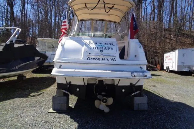 Slide: The Image of 2002 Chaparral Signature 260 boat on blocks, rear view, with flags, in wooded area. - 4