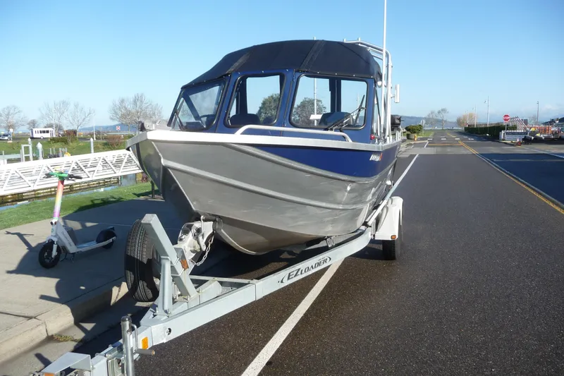 Slide: The Image of 2013 Thunder Jet 21 Luxor OB boat on trailer, parked near a dock. - 2