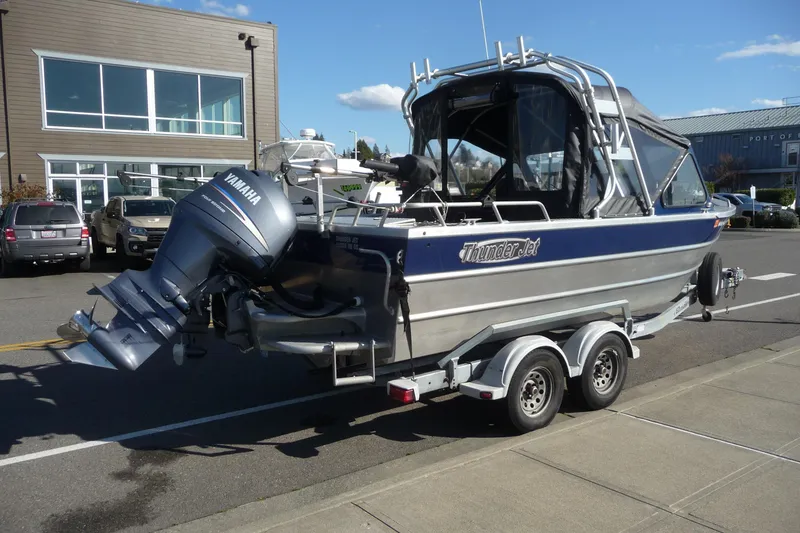 Slide: The Image of 2013 Thunder Jet 21 Luxor OB boat on trailer, parked near a building. - 4