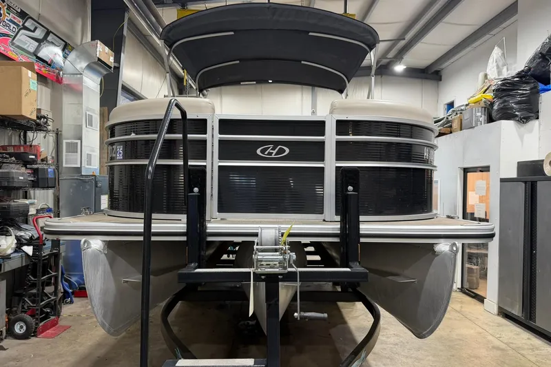 Slide: The Image of 2021 Harris Cruiser 210 pontoon boat in a workshop setting. - 1