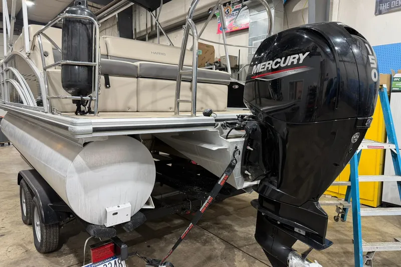 Slide: The Image of 2021 Harris Cruiser 210 pontoon boat with Mercury outboard motor in a garage setting. - 3