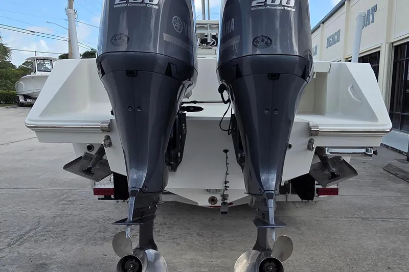 Slide: The Image of 2014 Jupiter 26 FS boat with dual Yamaha 200 outboard engines, parked outdoors. - 2