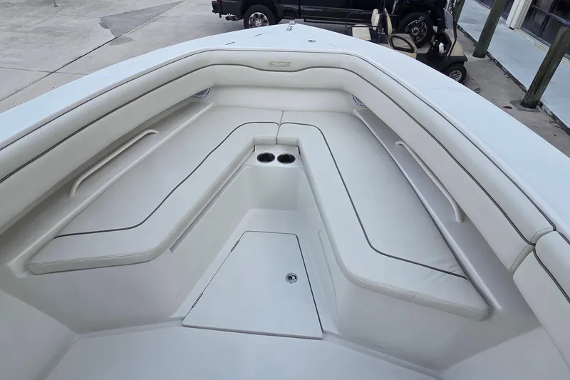 Slide: The Image of 2014 Jupiter 26 FS boat interior with white cushioned seating and cup holders. - 24