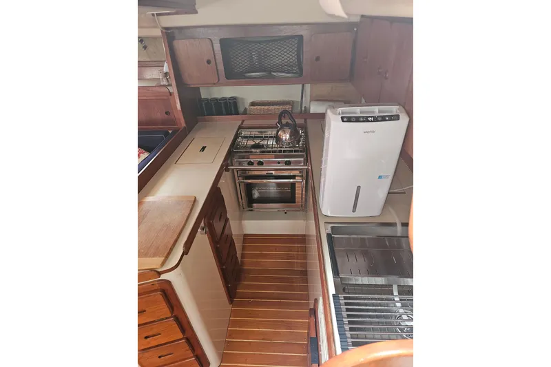 Slide: The Image of 1987 Morgan Classic 41 Center Cockpit kitchen with stove, wooden cabinetry, and modern appliances. - 23