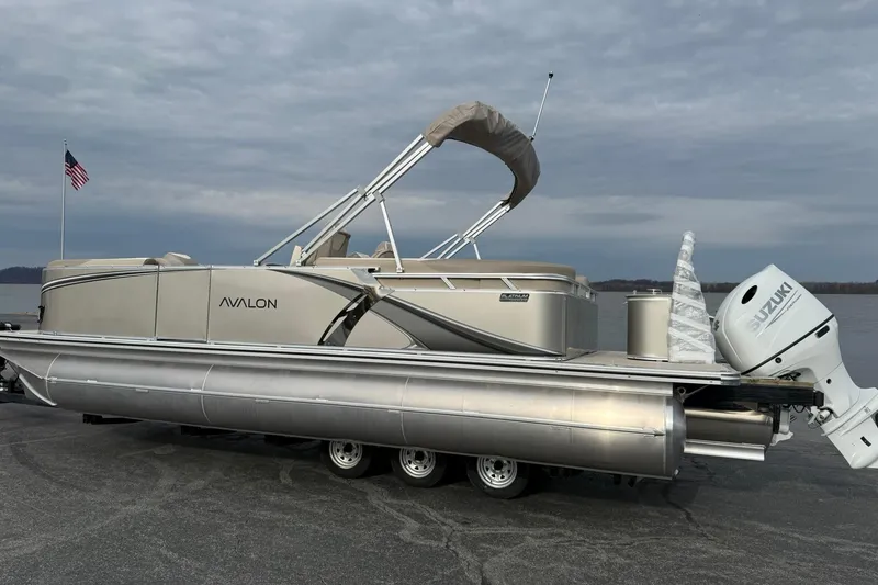 Slide: The Image of 2026 Avalon LSZ Quad Lounge pontoon boat with Suzuki outboard motor on a trailer. - 2