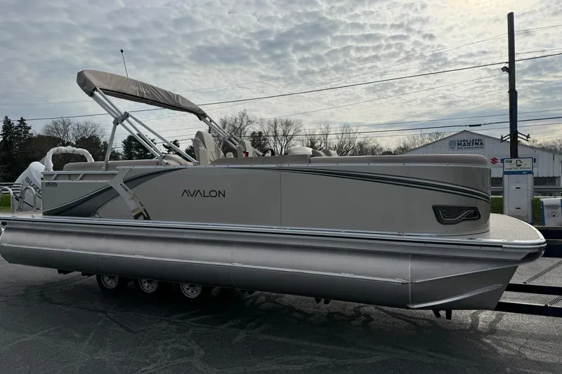 Slide: The Image of 2026 Avalon LSZ Quad Lounge 23' pontoon boat with canopy, parked outdoors. - 5