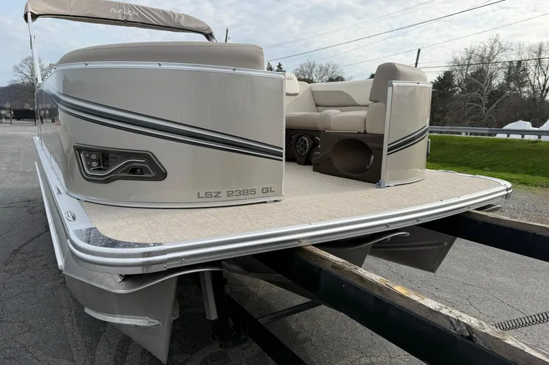 Slide: The Image of 2026 Avalon LSZ Quad Lounge 23' pontoon boat on trailer, showcasing sleek design and seating. - 6