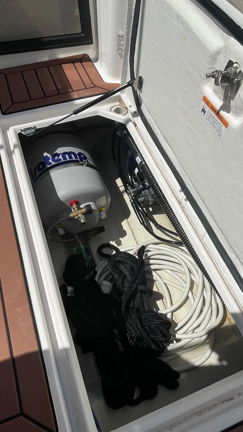 Slide: The Image of Storage compartment in 2024 Ranger Tugs R-25, featuring equipment and coiled cables. - 11