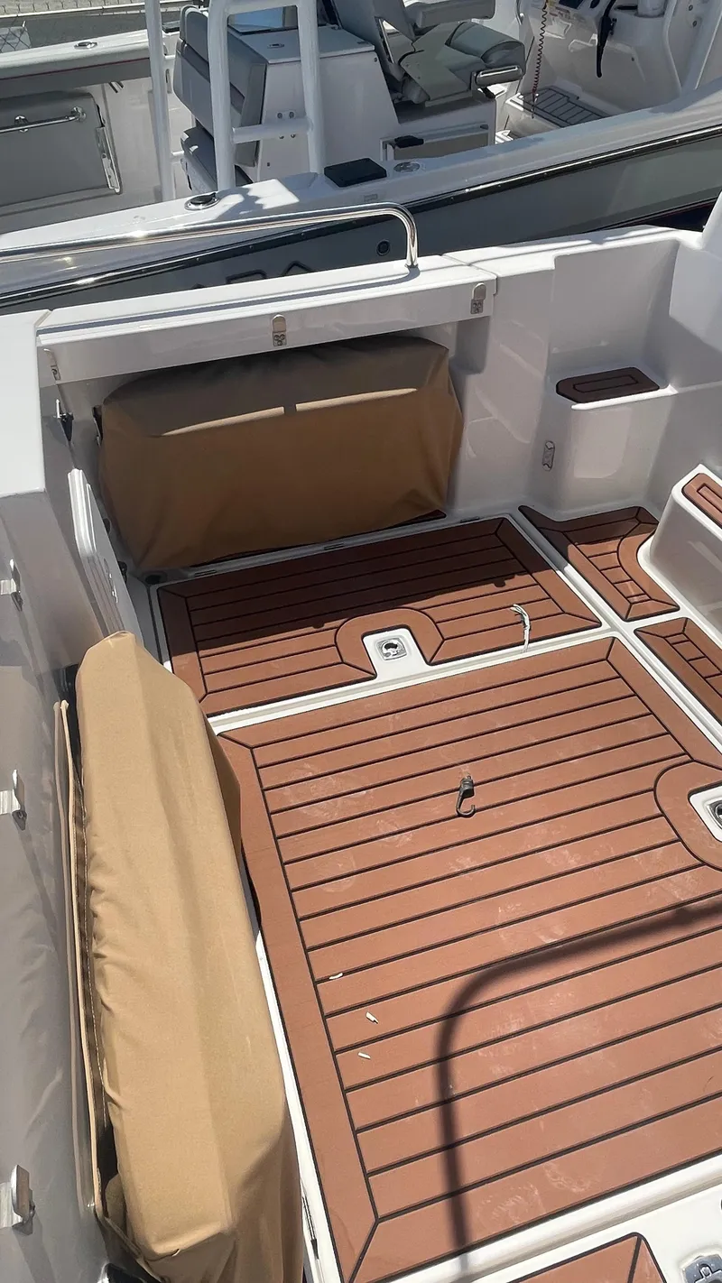 Slide: The Image of 2024 Ranger Tugs R-25 boat deck with wood finish and cushioned seating. - 13