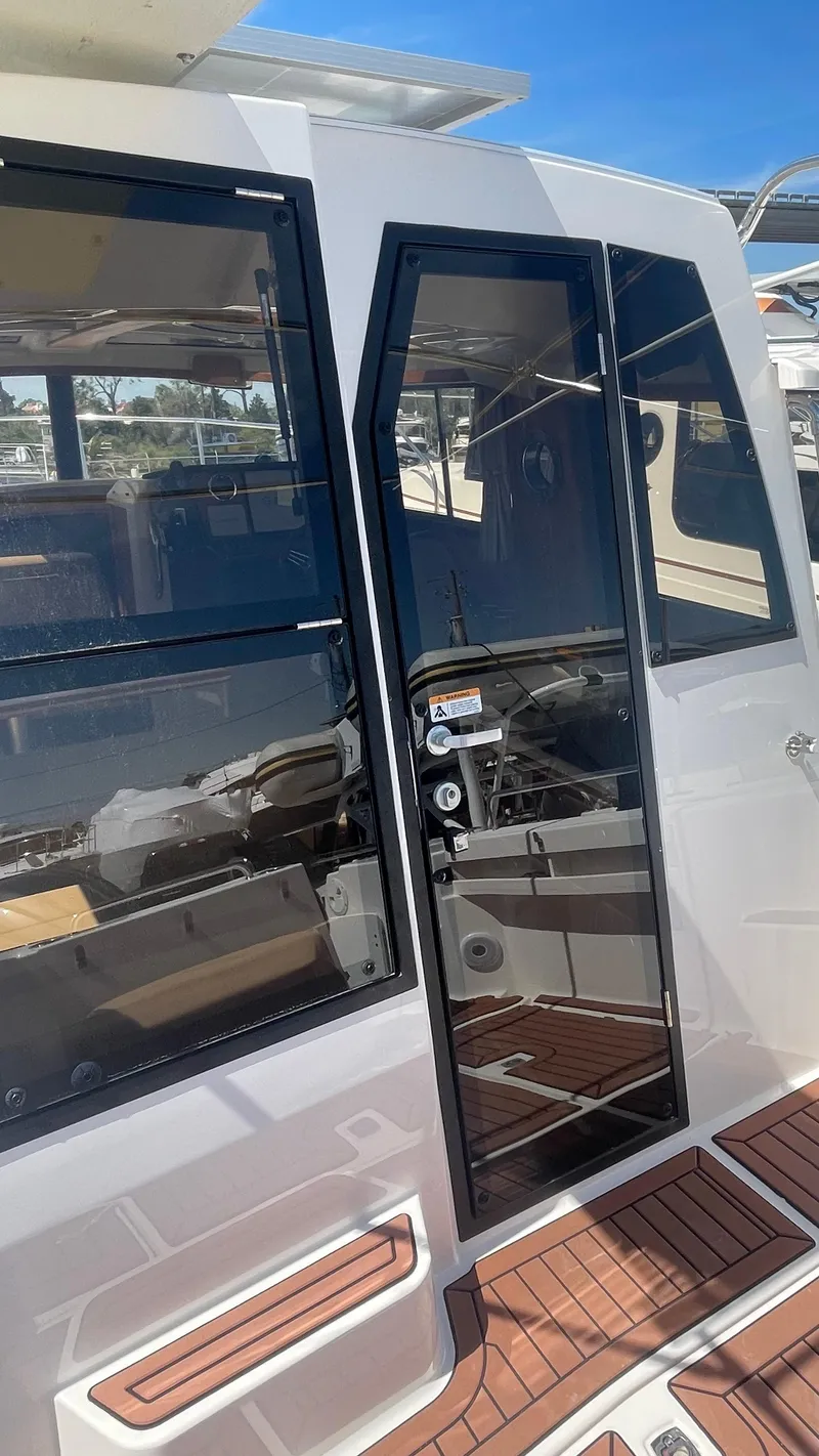 Slide: The Image of 2024 Ranger Tugs R-25 boat exterior with glass door and wooden deck. - 15