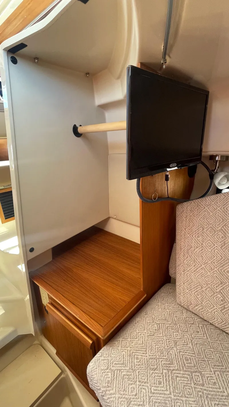 Slide: The Image of 2024 Ranger Tugs R-25 interior with TV and wooden cabinetry. - 26