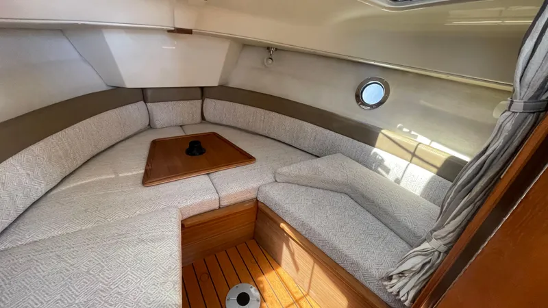 Slide: The Image of 2024 Ranger Tugs R-25 interior cabin with cozy seating and wooden table. - 28