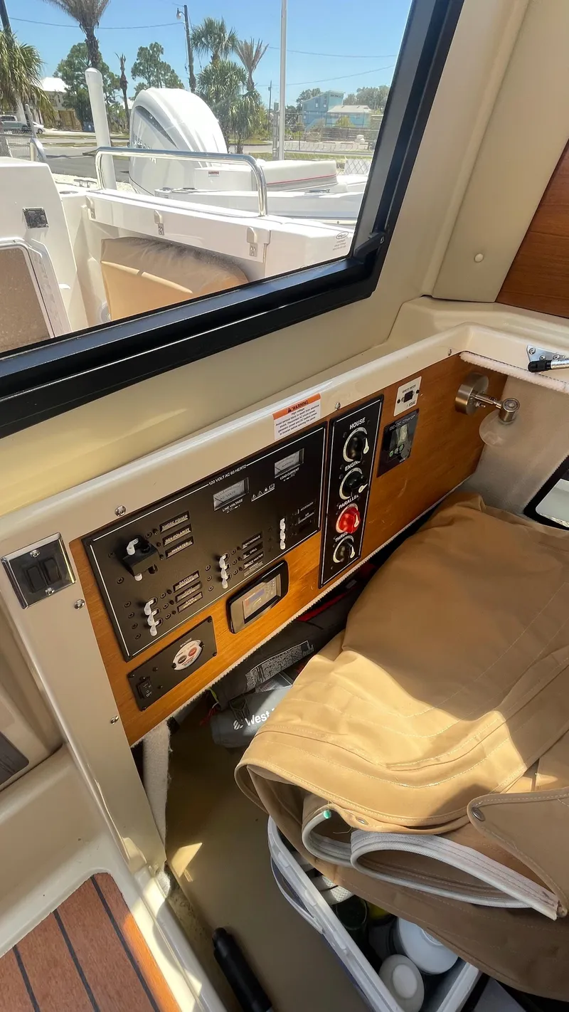 Slide: The Image of 2024 Ranger Tugs R-25 interior control panel with window view and storage area. - 29