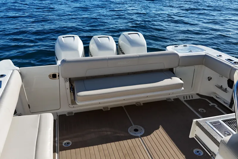 Slide: The Image of 2016 Boston Whaler 345 Conquest boat interior with triple engines and seating, on open water. - 16