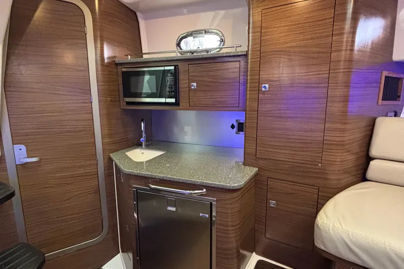 Slide: The Image of Interior of 2016 Boston Whaler 345 Conquest, featuring a compact kitchen with wood finish. - 22