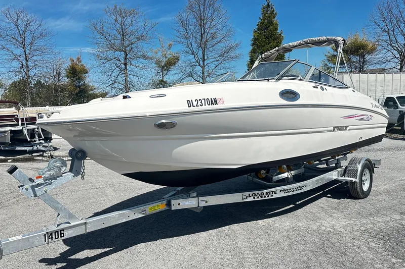The Image of 2012 Stingray 234 LR boat on trailer, parked outdoors under clear blue sky. - 0