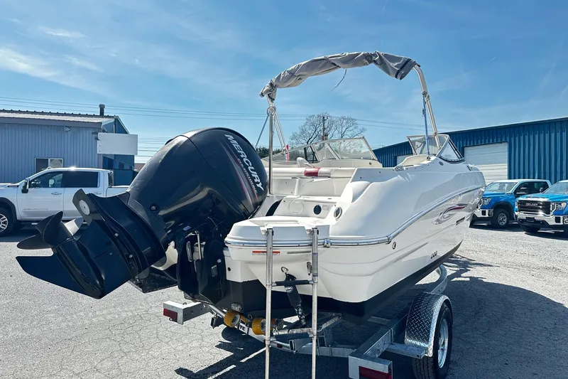 Slide: The Image of 2012 Stingray 234 LR boat on trailer with Mercury outboard motor, parked outdoors. - 2