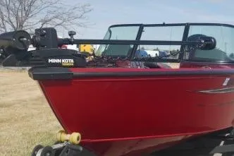 Slide: The Image of 2023 Ranger VS1882 WT boat with Minn Kota motor, red exterior, parked on grass. - 4