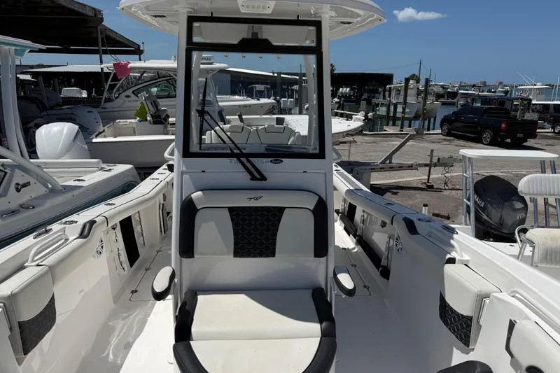 Slide: The Image of 2022 Tidewater 256 LXF boat interior at marina, showcasing seating and console. - 10