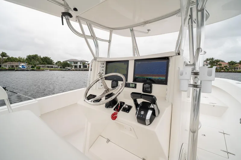 Slide: The Image of 2006 Venture Center Console boat interior with steering wheel and navigation screens on a calm waterway. - 26