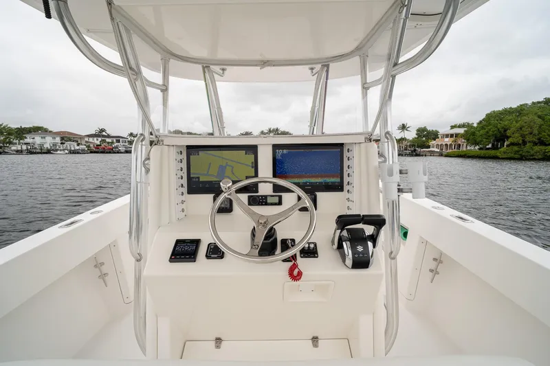 Slide: The Image of 2006 Venture Center Console boat dashboard with navigation screens and steering wheel on a calm waterway. - 27